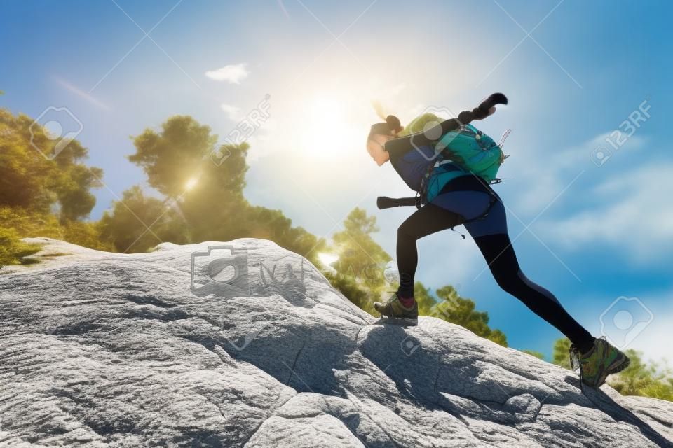 young asian woman hiker climbing rock on mountain peak cliff