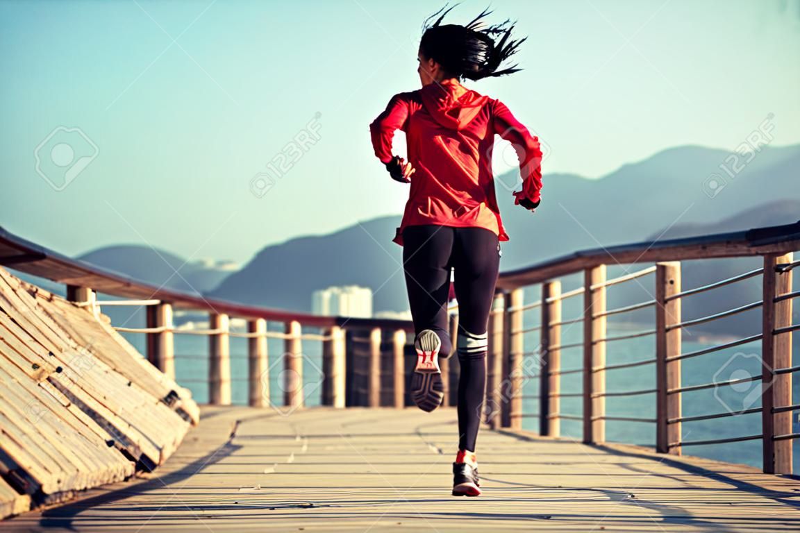 Sportowa fitness biegaczka biegająca po nadmorskiej promenadzie