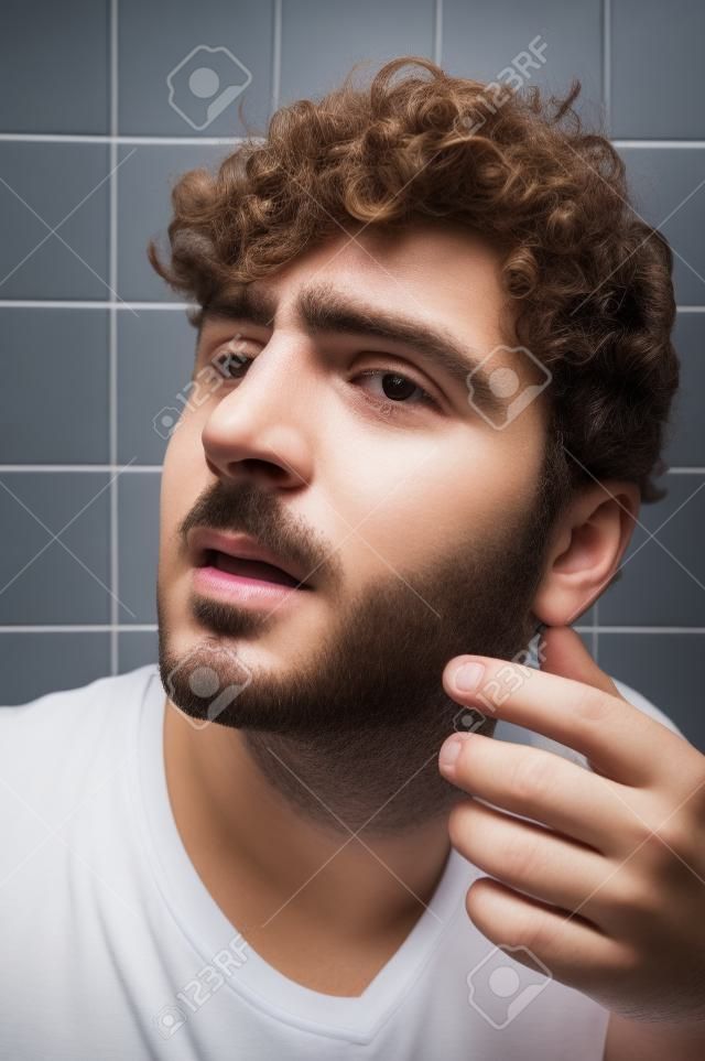 Curly haired man in bathroom with bad nose bleed