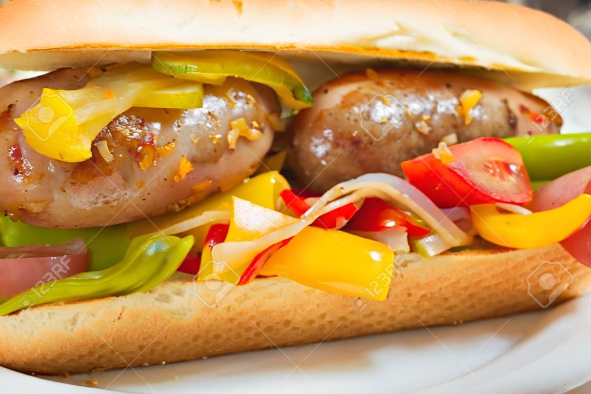 Fried sausage onions and red green and yellow bell peppers on sandwich bun