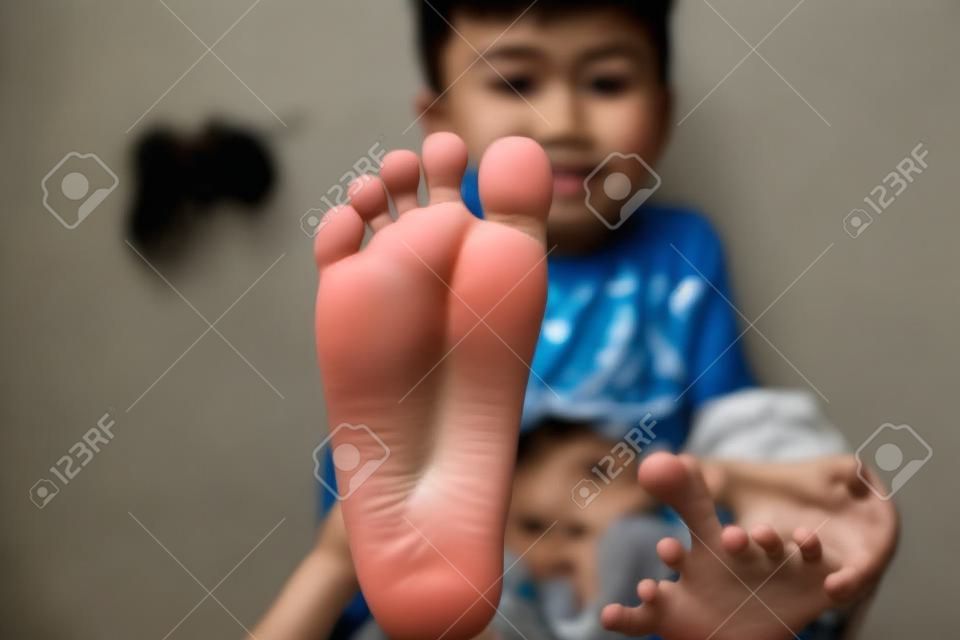 Asian boy showing dirty feet.