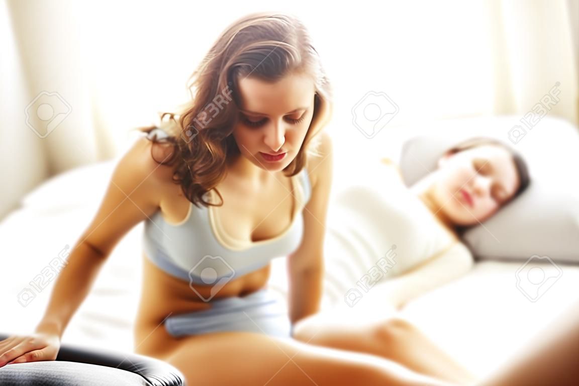 침실에서 복통이있는 여성을 보여주는 그림
