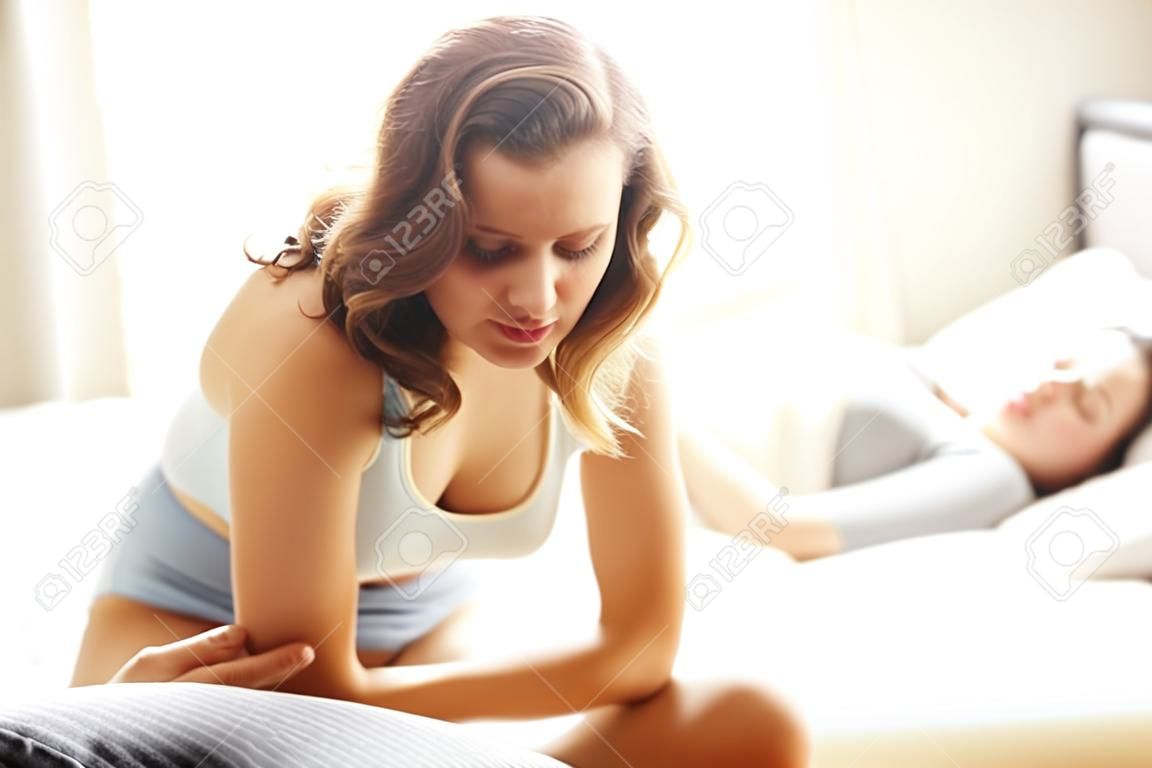 Imagen que muestra la mujer que tiene dolor de estómago en el dormitorio