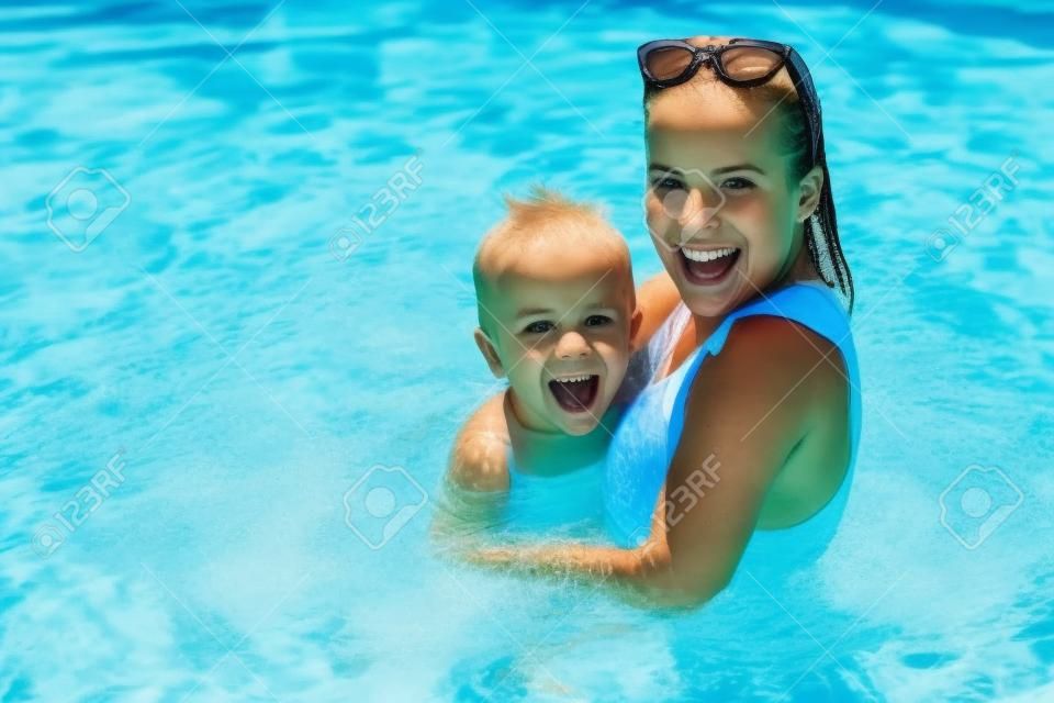 Chico lindo con su madre jugando en la piscina durante el verano