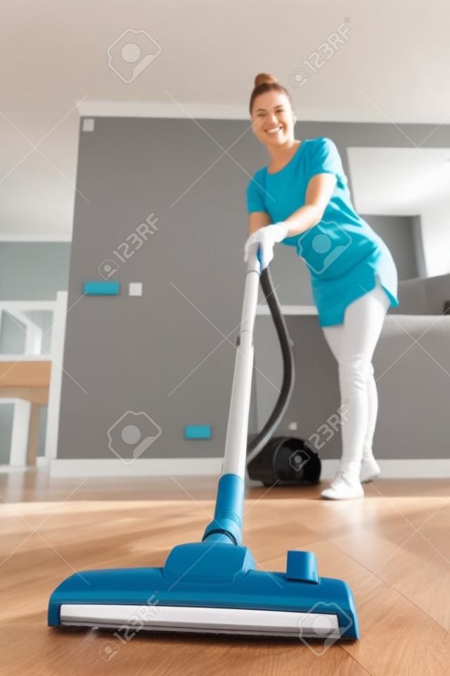 진공 청소기로 집을 청소하는 여성 사진