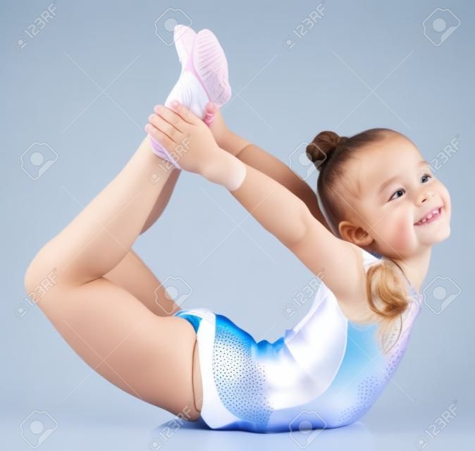 Молодая симпатичная девушка делает гимнастику на белом фоне