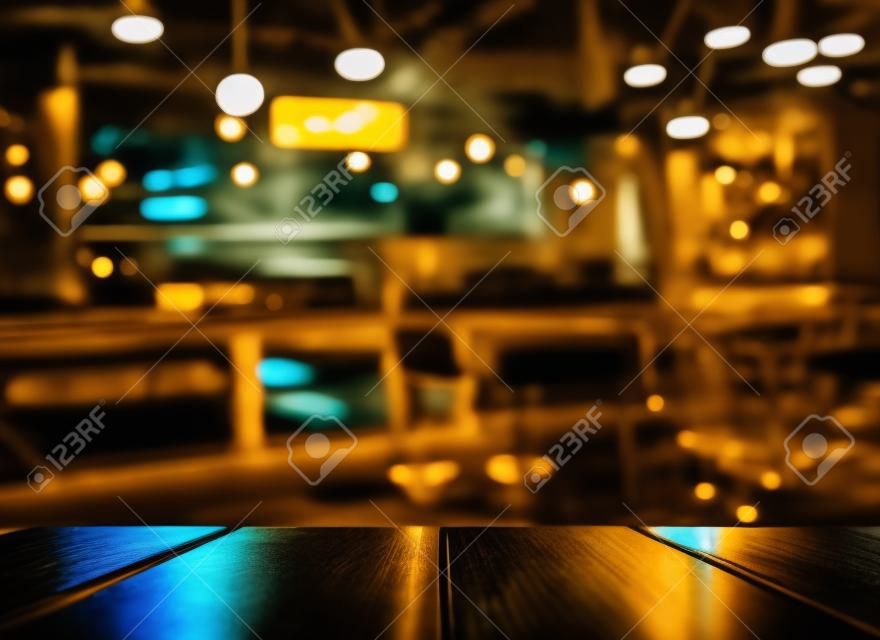 Parte superior de la mesa de madera con reflejo de luz con amarillo abstracto desenfoque bar o club en el fondo de la noche oscura