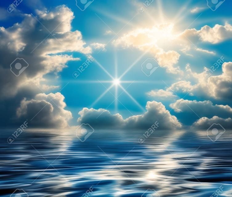 輝煌的藍色的天空與雲大和閃亮的陽光在水面上反射和波