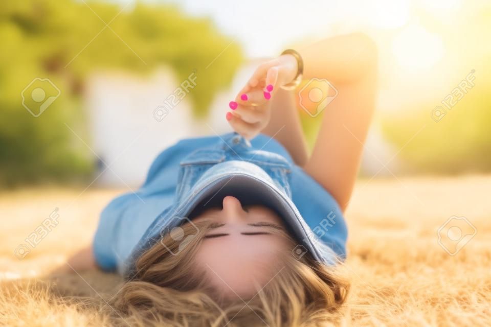 Donna nervosa che si morde le unghie mentre si sdraia sulla schiena e indossa occhiali da sole - Ragazza che si mordicchia le unghie all'esterno