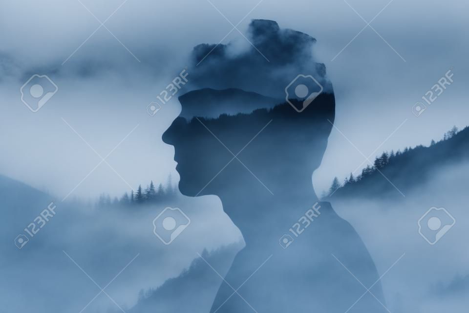 Sylwetka mężczyzny patrzącego na góry i drzewa we mgle