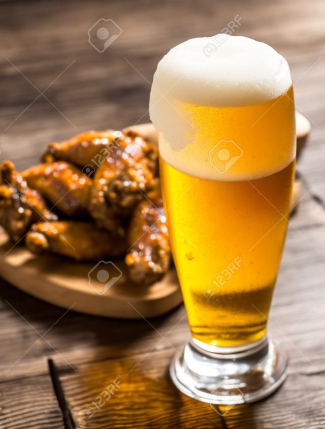 glass of fresh beer and fried chicken wings on wooden table