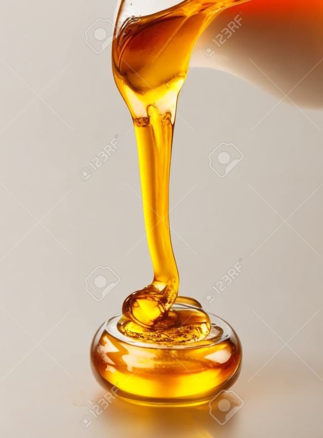 꿀을 붓는 것은 흰색 배경에 고립