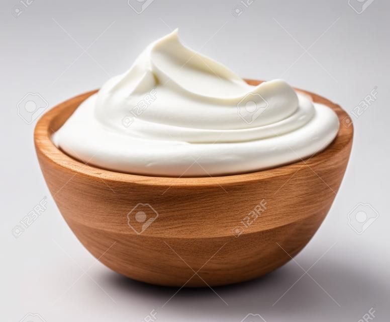 houten kom van geklopte zure room yoghurt geïsoleerd op witte achtergrond