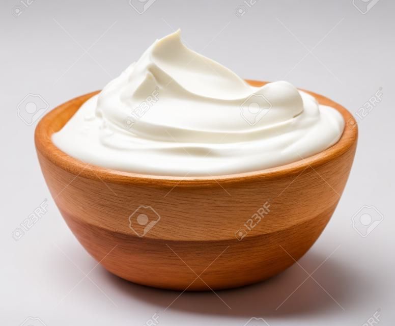 houten kom van geklopte zure room yoghurt geïsoleerd op witte achtergrond