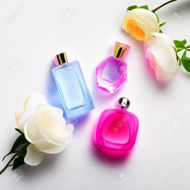 Parfümös palackok virágokkal világos háttéren. Illatszerek, kozmetikumok, illatgyűjtés. Lapos feküdt