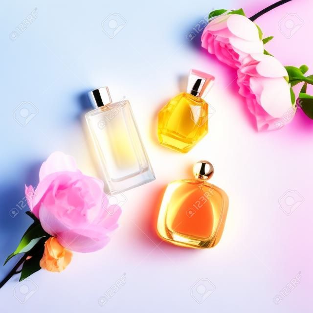明るい背景に花と香水瓶。香水、化粧品、香りのコレクション。フラットを置く