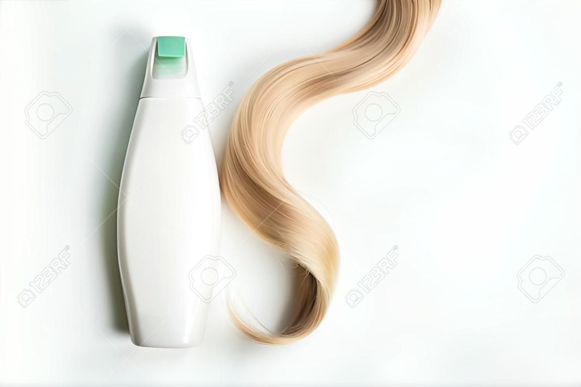 Shampoo or conditioner bottle and lock of curly blonde hair isolated on light background, top view. Flat lay, copy space for text. Hair care cosmetics, beauty haircare products, hair treatment