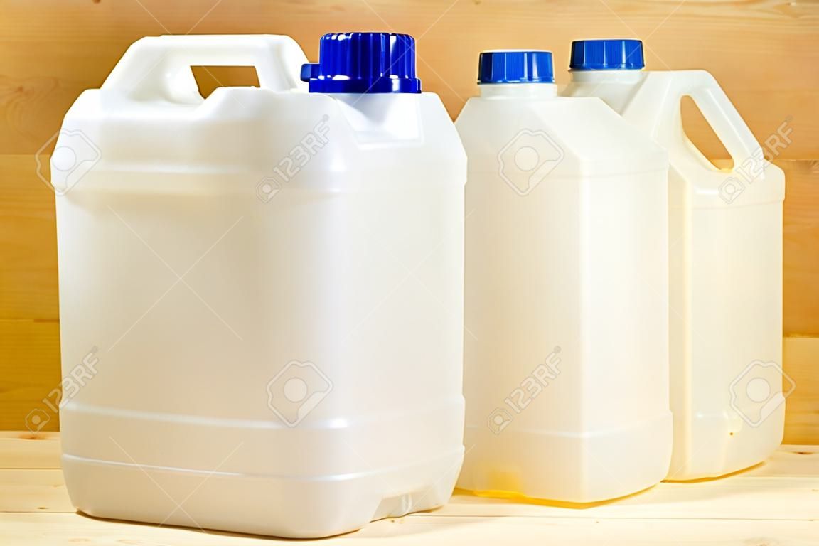 A pair of plastic gallons of different configuration on wooden background