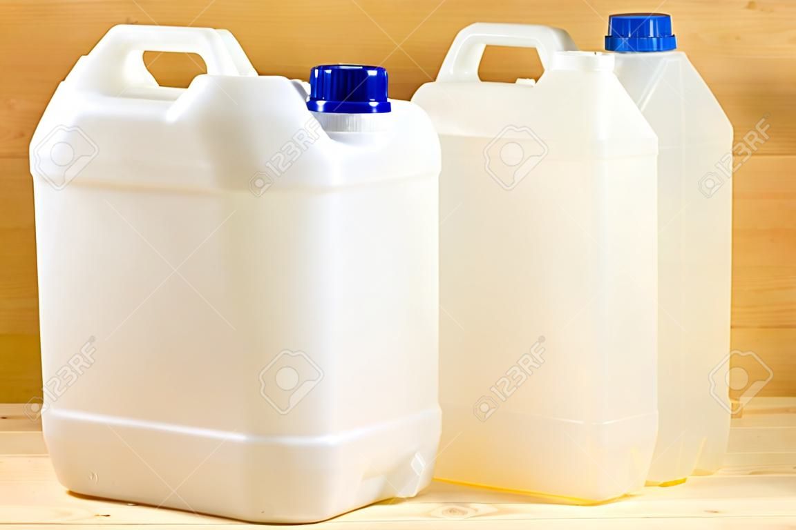 A pair of plastic gallons of different configuration on wooden background