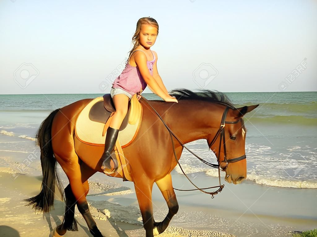 Mädchen Kind ein Pferd auf dem Hintergrund des Meeres Reiten