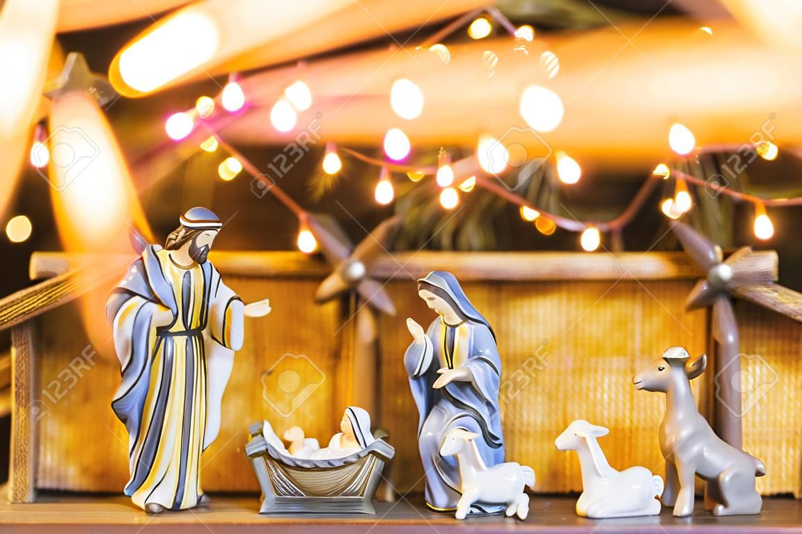 Christmas Manger scene with figurines including Jesus, Mary, Joseph and sheep. Focus on mother! Lights trail in front of camera.