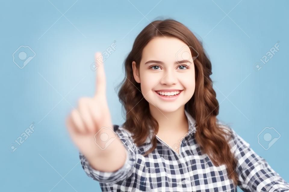 Chica estudiante alegre feliz tocando el tablero de cristal con el dedo. Mujer joven en camisa de cuadros casual que se encuentran aisladas sobre fondo blanco. Concepto de publicidad o tecnología.