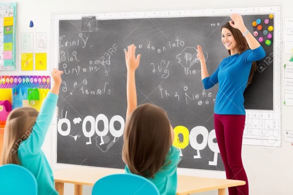 Young woman teacher teaching kids in kindergarten classroom