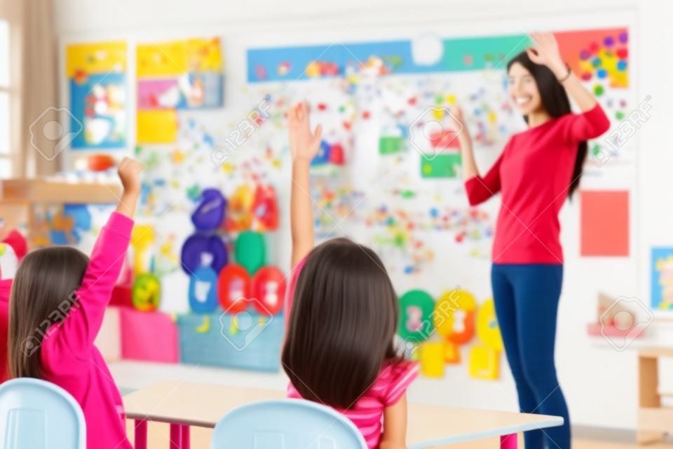 Fiatal nő tanár tanítja a gyerekeket az óvodai osztályteremben