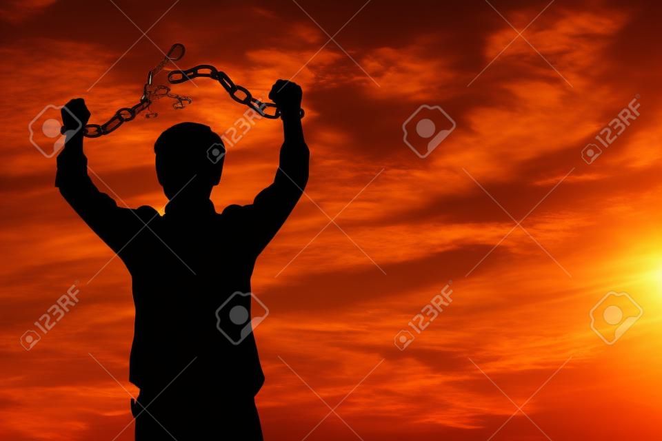 Silhouette afbeelding van een zakenman met gebroken kettingen bij zonsondergang