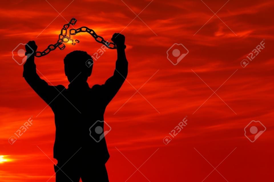 Image de la silhouette d'un homme d'affaires avec des chaînes brisées au coucher du soleil
