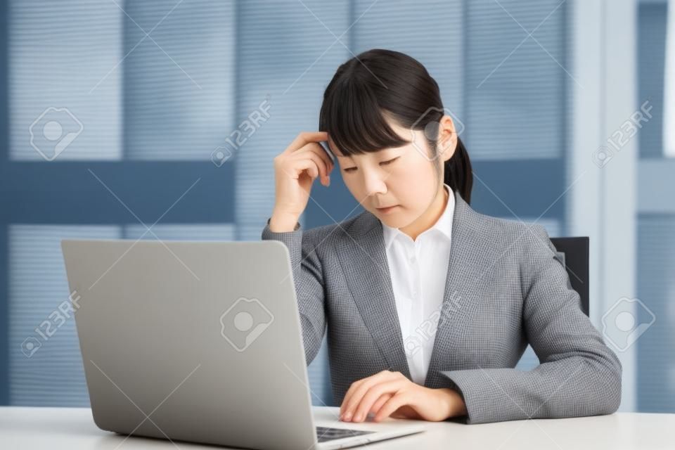 ノートパソコンを操作しながら心配している日本人女性実業家