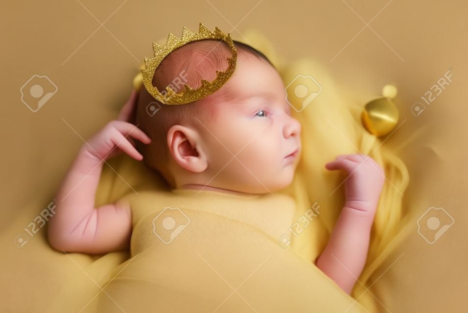 Portrait of a newborn baby boy with a golden crown