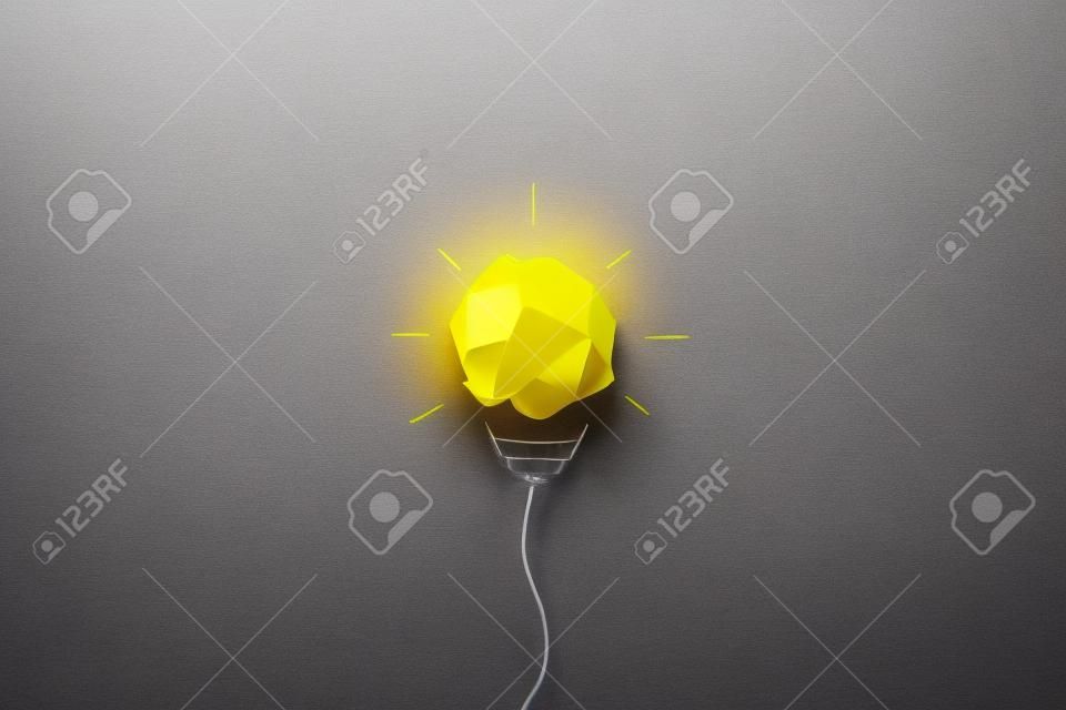 創造的な思考のアイデアと革新の概念。黄色の背景に電球のシンボルと紙くずボール