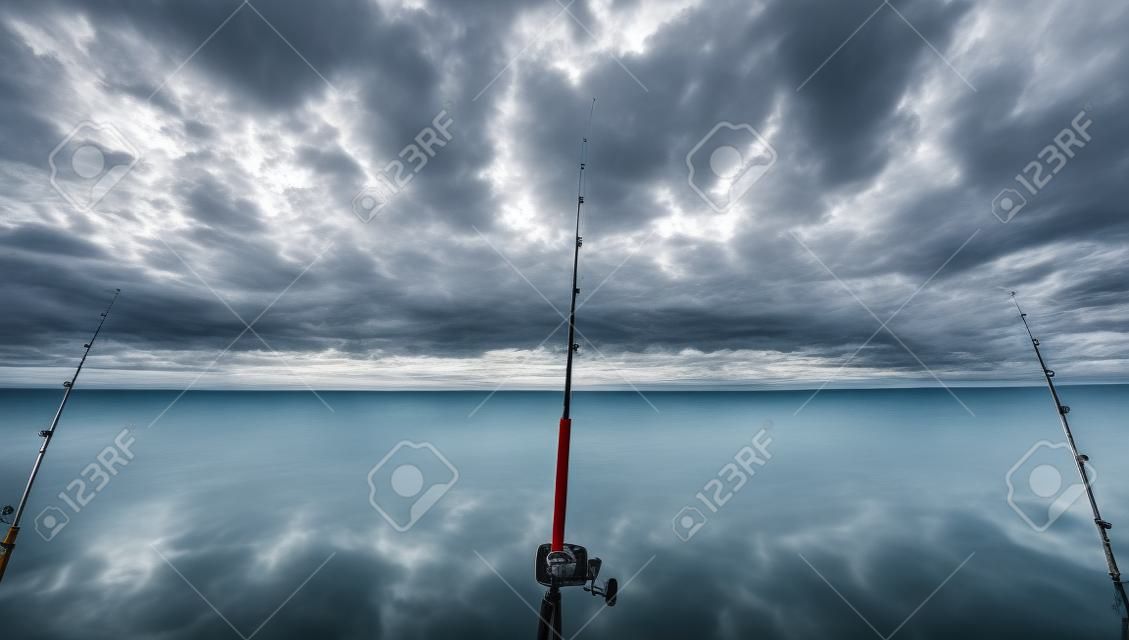 Cañas de pescar en barco más de un hermoso paisaje marino nublado