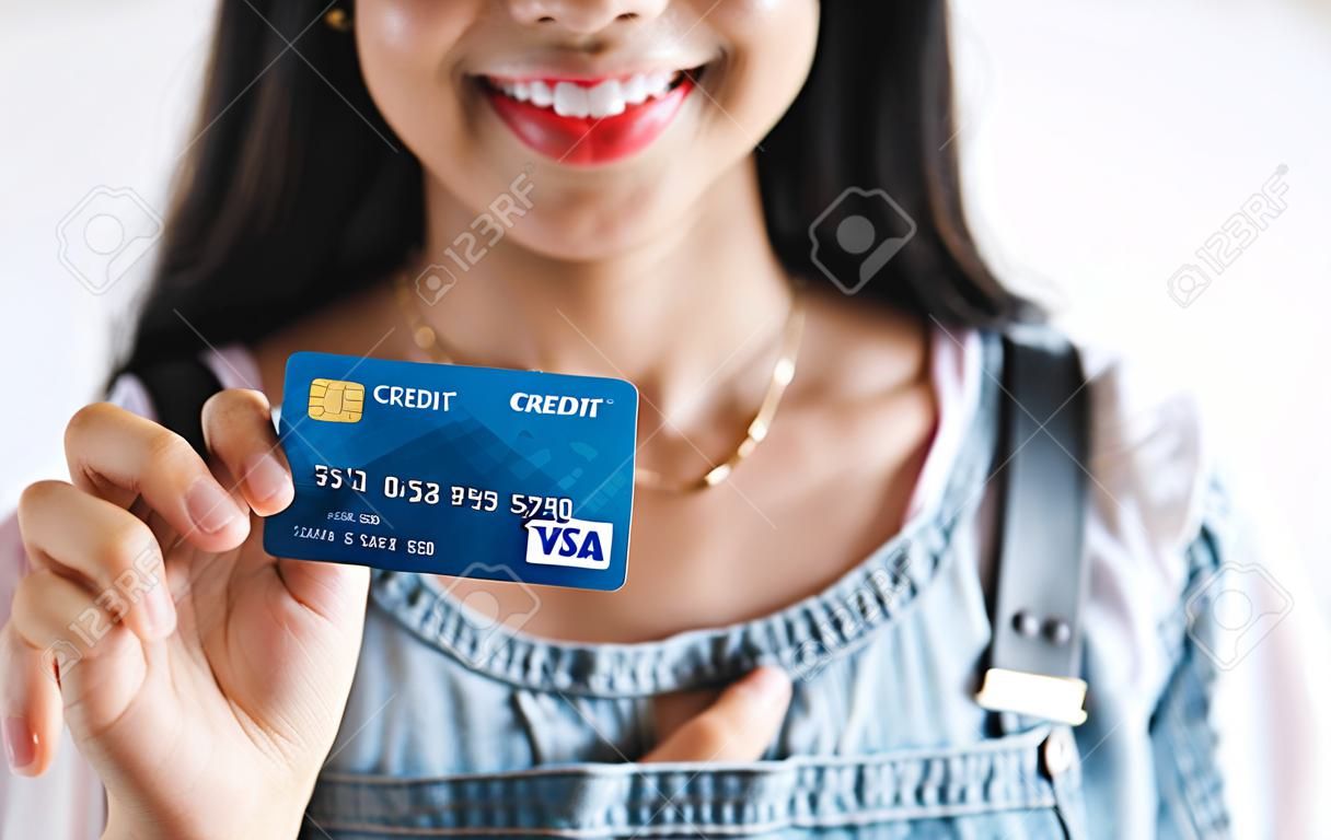Joven hispana sosteniendo una tarjeta de crédito azul aislada sobre fondo blanco en América Latina