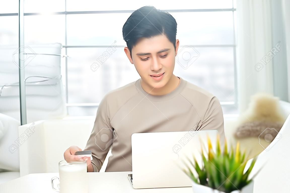 Portrait of a casual smiling young man make payment using credit card