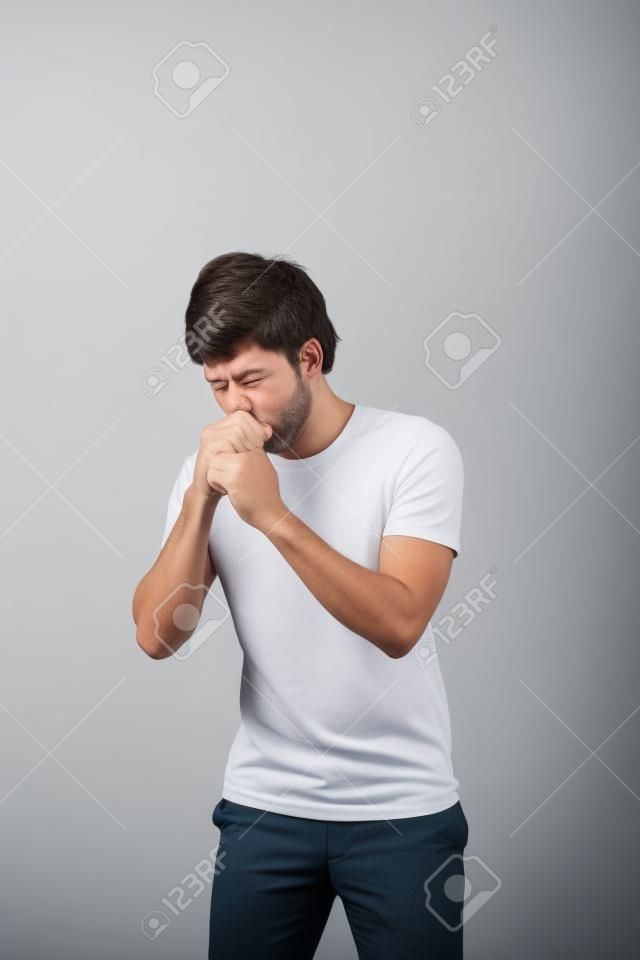 handsome man coughing into his fist, isolated on a white background