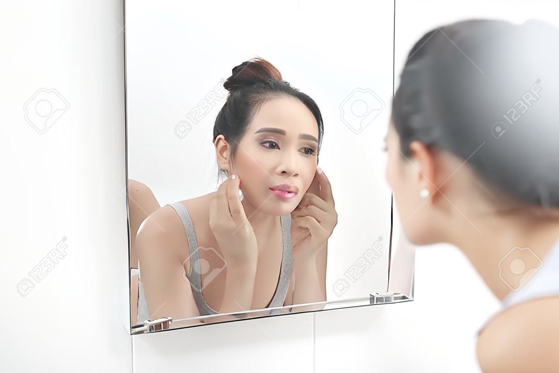 Protección de la piel. Mujer aplicar crema para la piel en el rostro delante del espejo