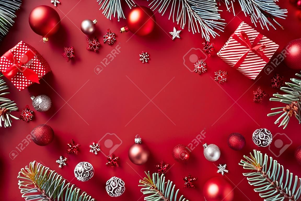 Flachrahmen mit roten Weihnachtskugeln, Fichtenzweigen und Geschenkbox auf rotem Grund