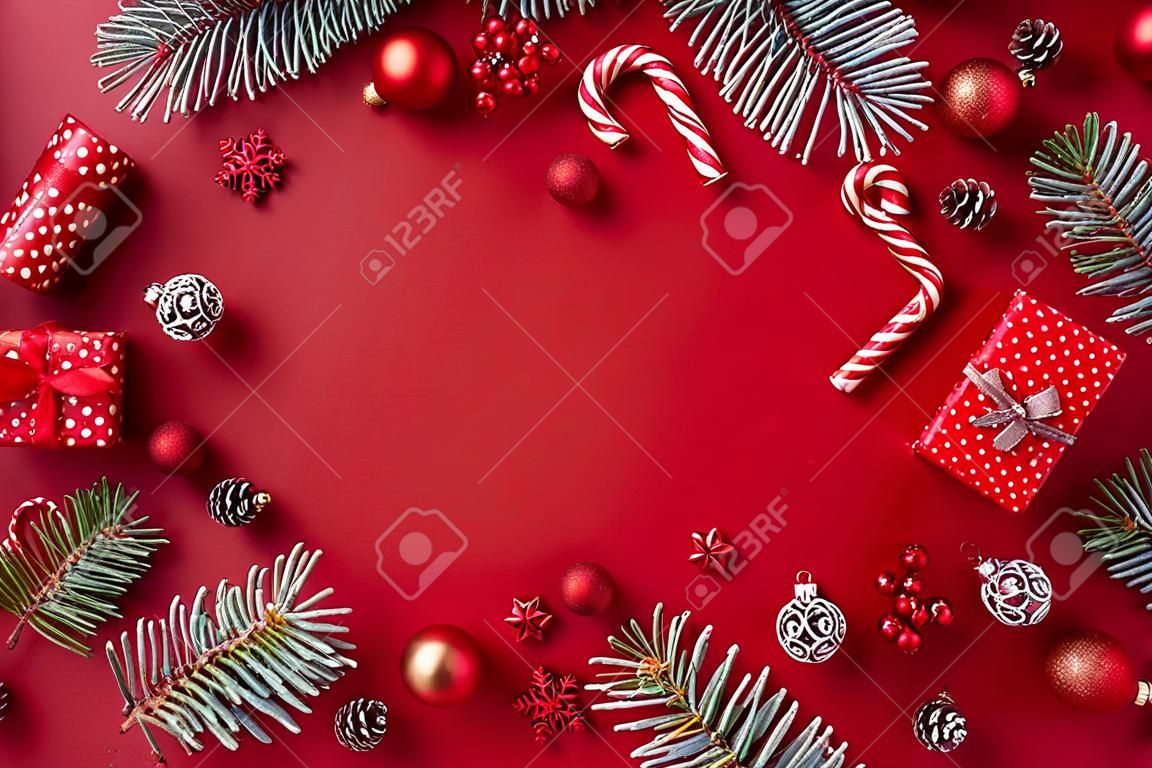 Flat lay frame with red christmas balls, spruce branches and gift box on a red background