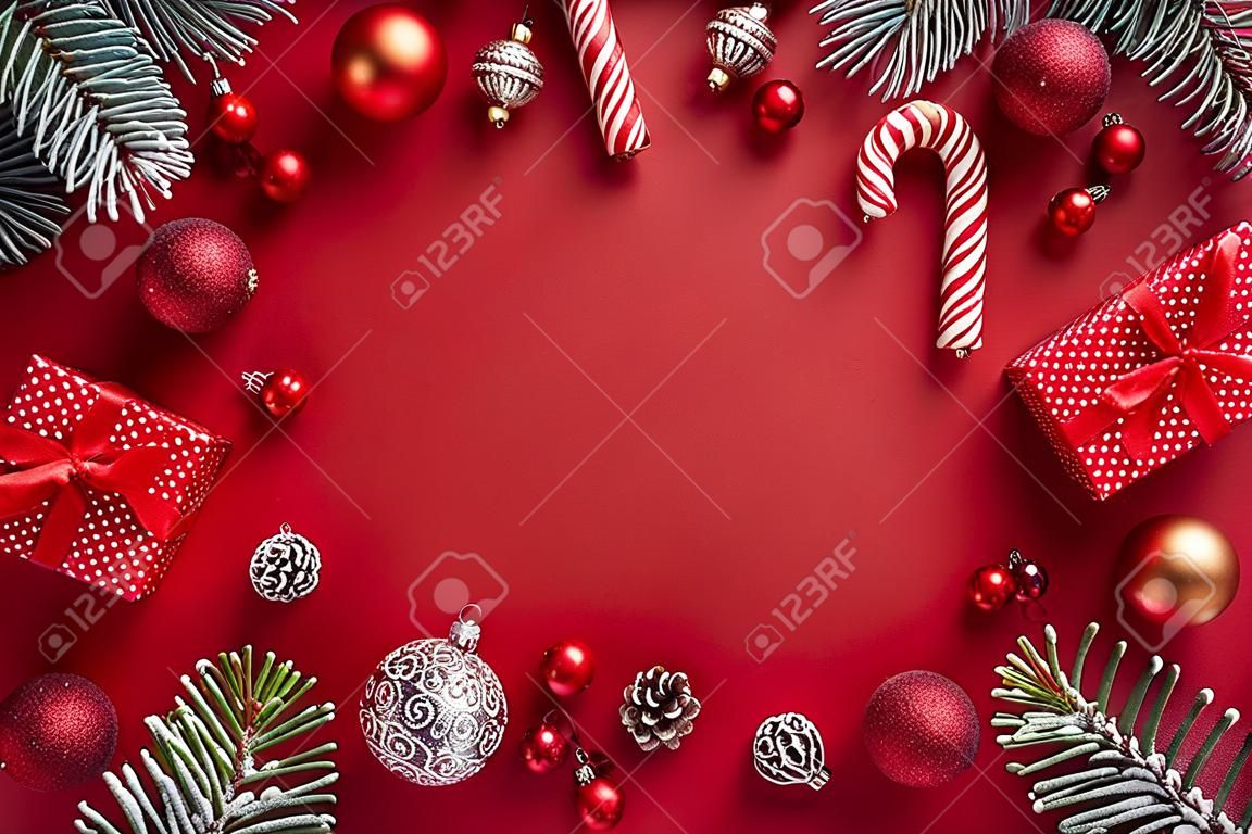 Flat lay frame with red christmas balls, spruce branches and gift box on a red background