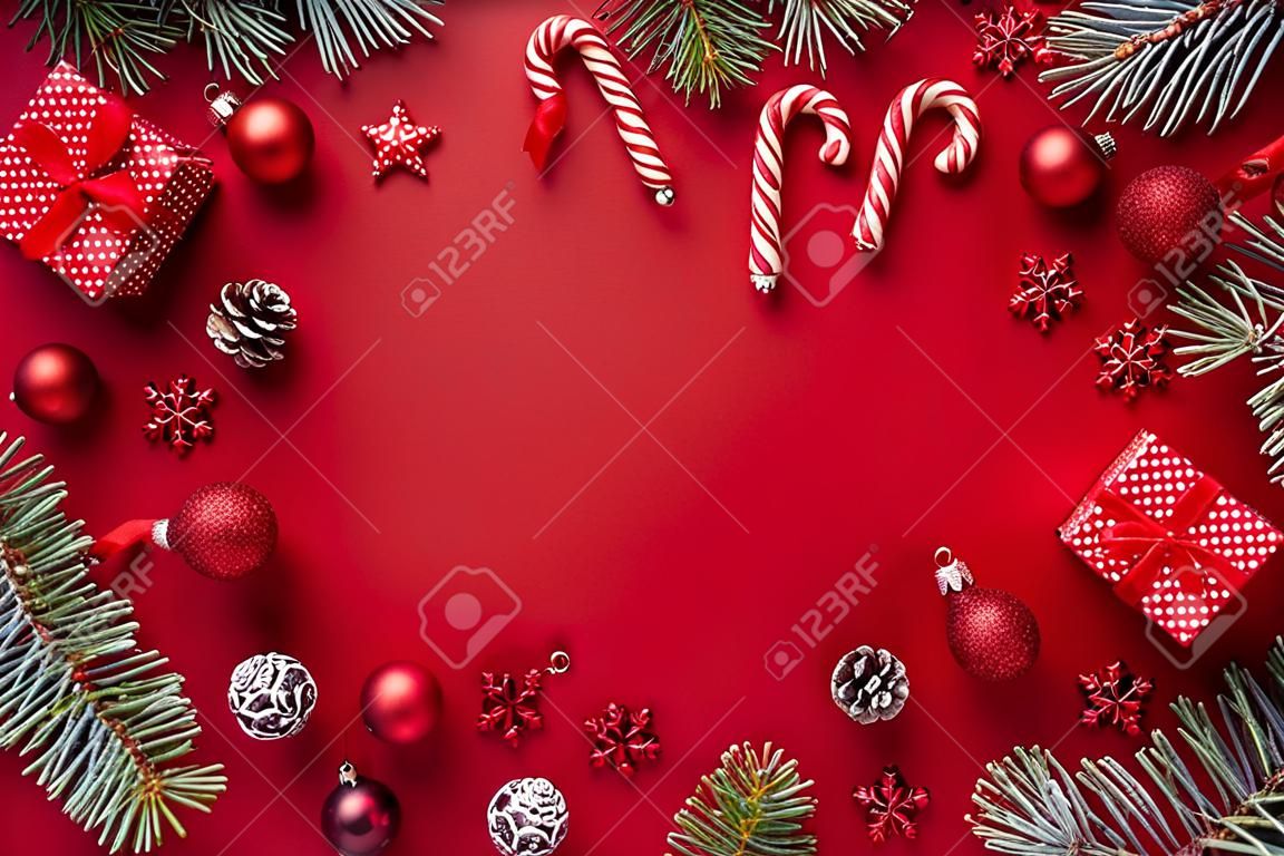 Moldura plana com bolas vermelhas de Natal, ramos de abeto e caixa de presente em um fundo vermelho