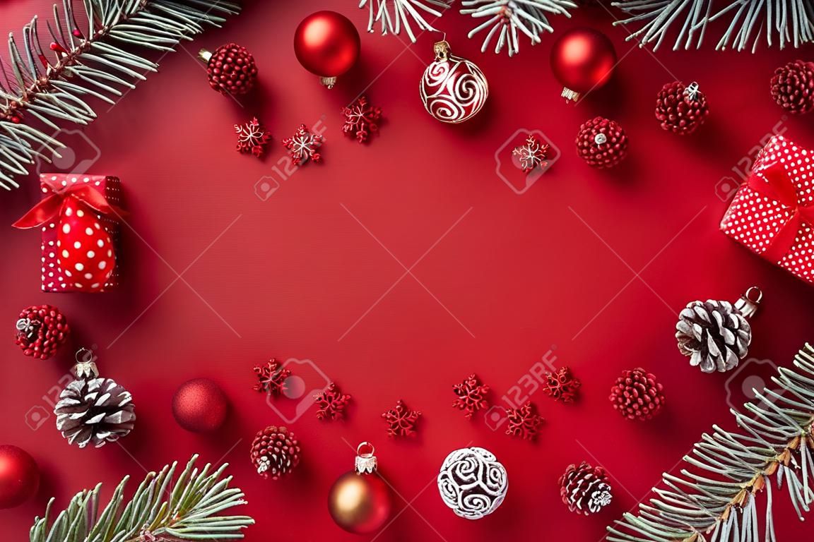 Flachrahmen mit roten Weihnachtskugeln, Fichtenzweigen und Geschenkbox auf rotem Grund