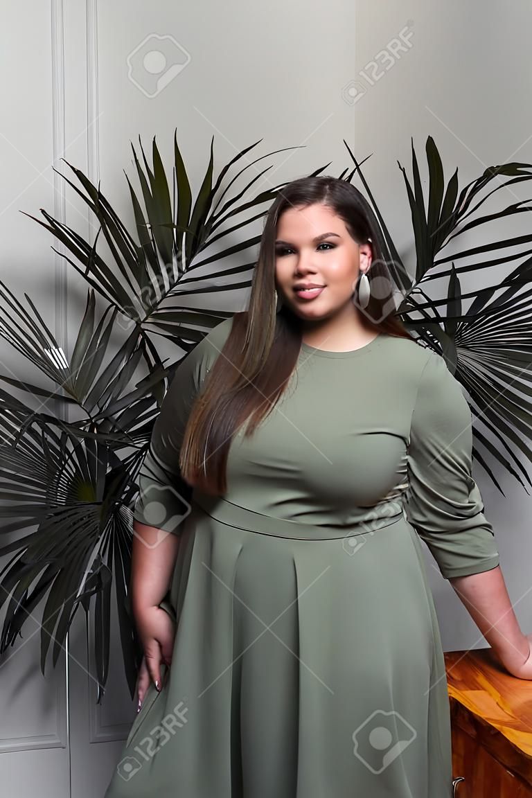 Plus size fashion model in casual clothes, fat woman on beige studio background, overweight female body