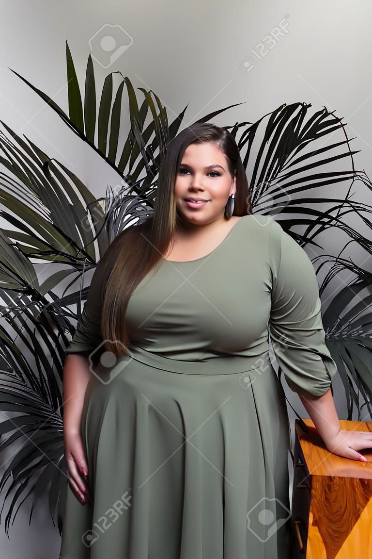 Plus size fashion model in casual clothes, fat woman on beige studio background, overweight female body
