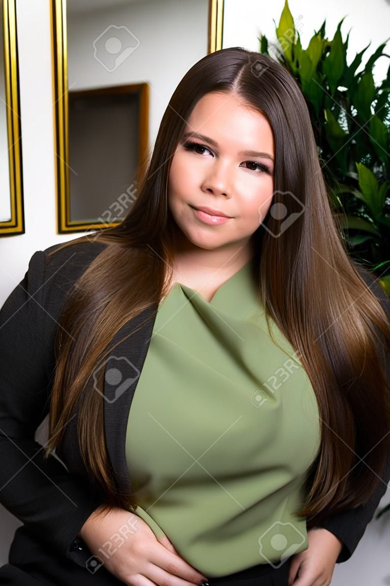 Close up portrait of young beautiful lady wearing stylish classic clothes posing at the studio. Plus size model. Female fashion concept