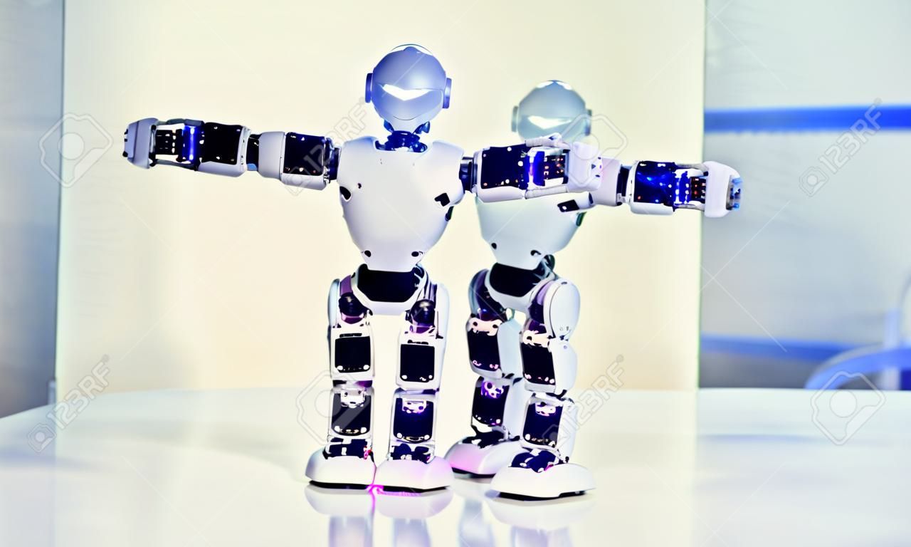 Kleine Cyborg Roboter, Humanoide mit Gesicht, leuchtende Augen, Körpertänze und macht verschiedene Bewegungen der Hände, Füße zur Musik. Künstliche Intelligenz. AI Smart Robot.Concept von 4.0 industrielle Revolution