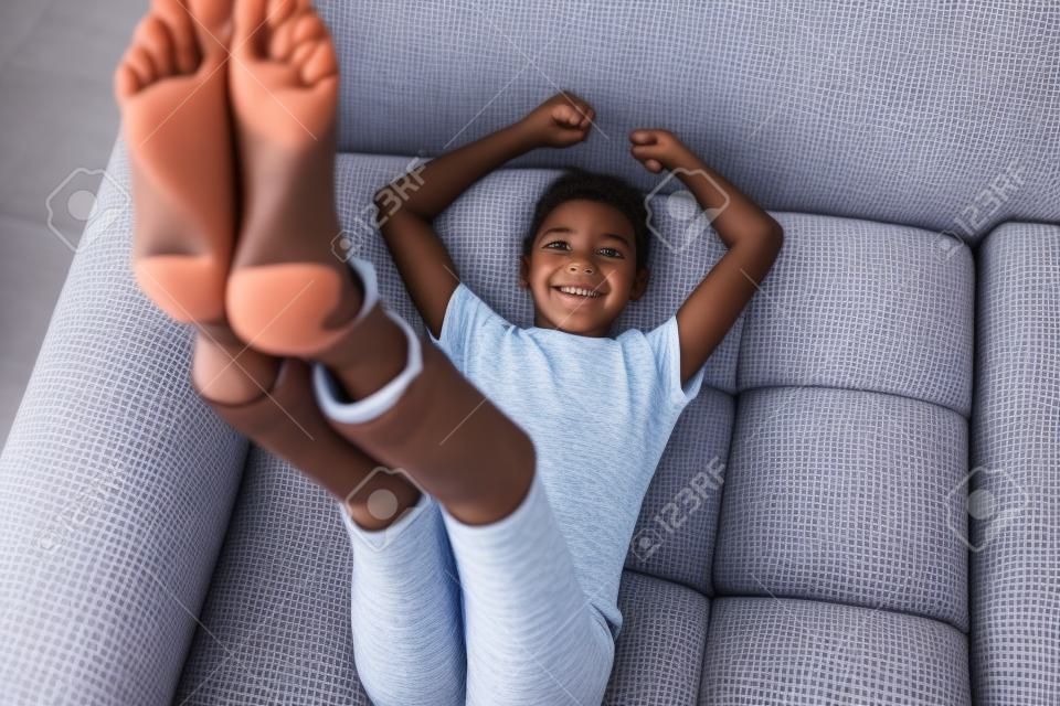 Preteen girl lying on couch with her feet raising up high