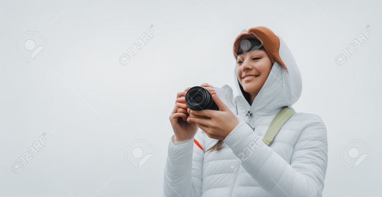 professional photographer tourist traveler standing on on a white background holding in hands digital photo camera, hiker view from front taking photography, closeup girl enjoy relax holiday hobby concept