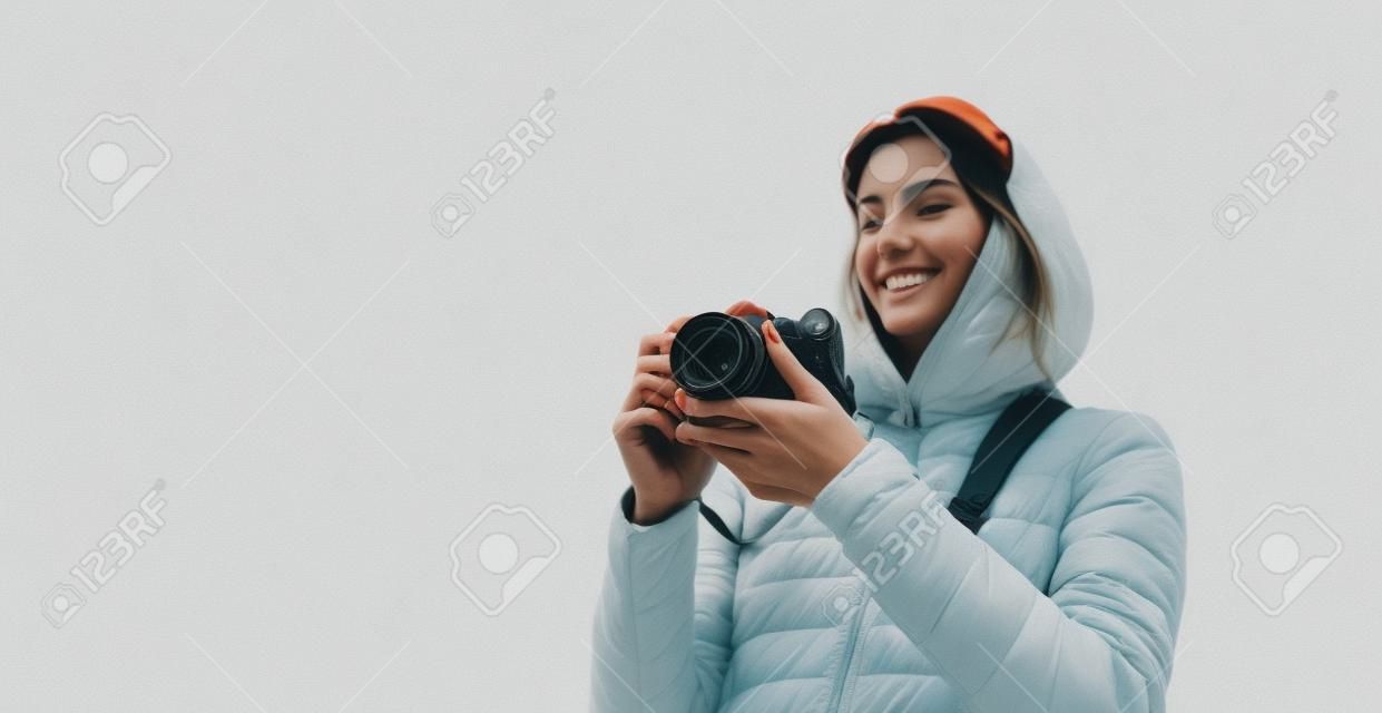 professional photographer tourist traveler standing on on a white background holding in hands digital photo camera, hiker view from front taking photography, closeup girl enjoy relax holiday hobby concept